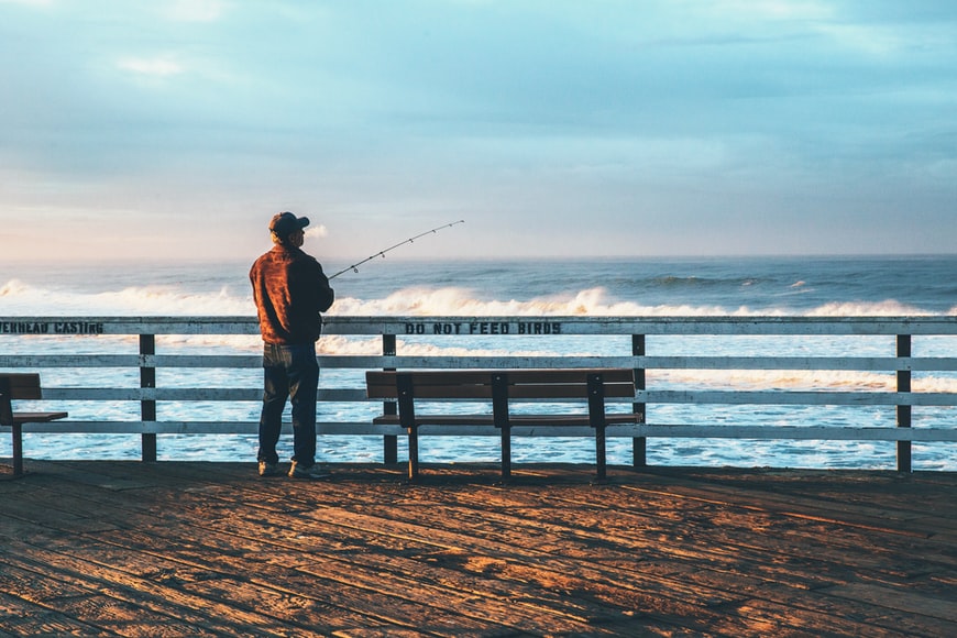 Man fishing off ocean pier