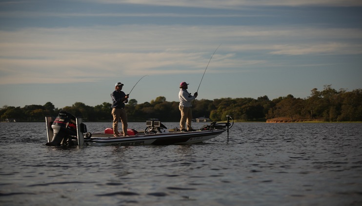 Two people on a fishing boat in middle of water bass fishing in Texas area