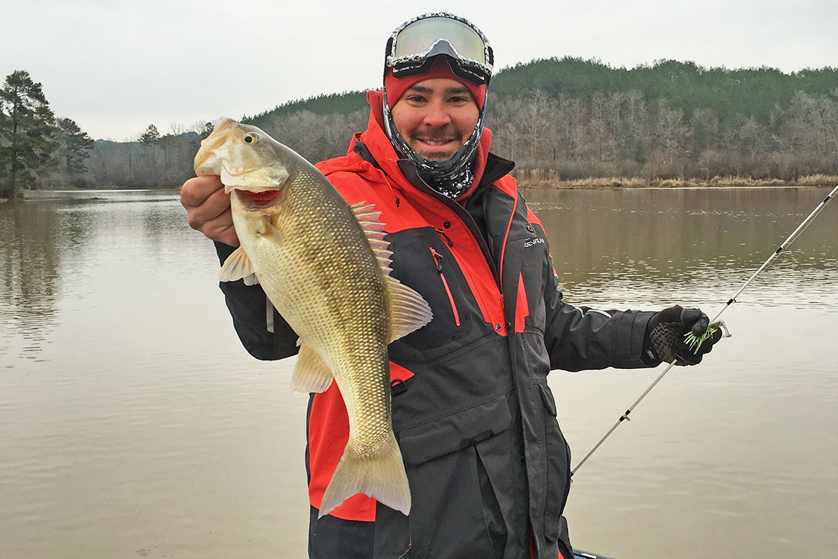 Man bass fishing in the Fall and Winter at a lake when it is cold