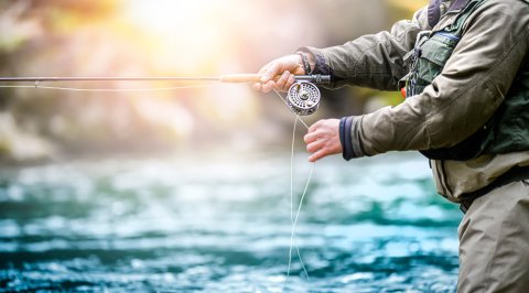 bass vs trout fishing: man fishing by the river