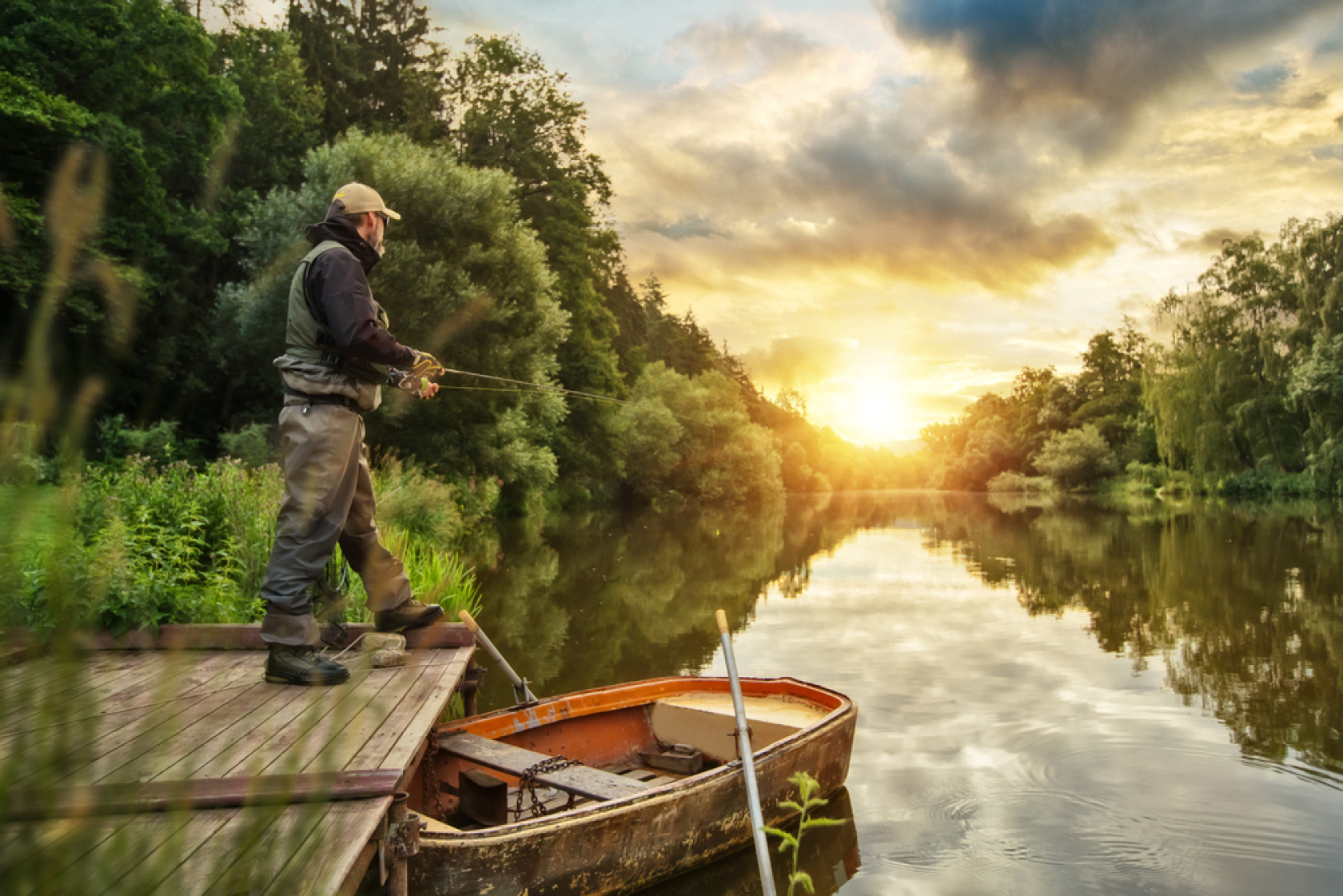 Man standing on the deck and fishing in the sunset