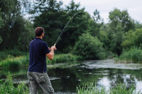 Fisherman demonstrating bass fishing retrieval techniques.